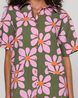 Person wearing a shirt dress with a floral pattern on a plain background