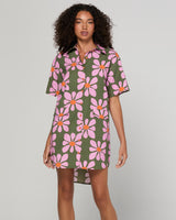 Woman wearing a floral dress with pink flowers on a plain background