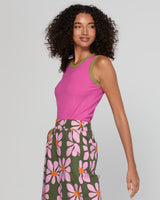 Woman wearing a pink top and green floral skirt on a plain background