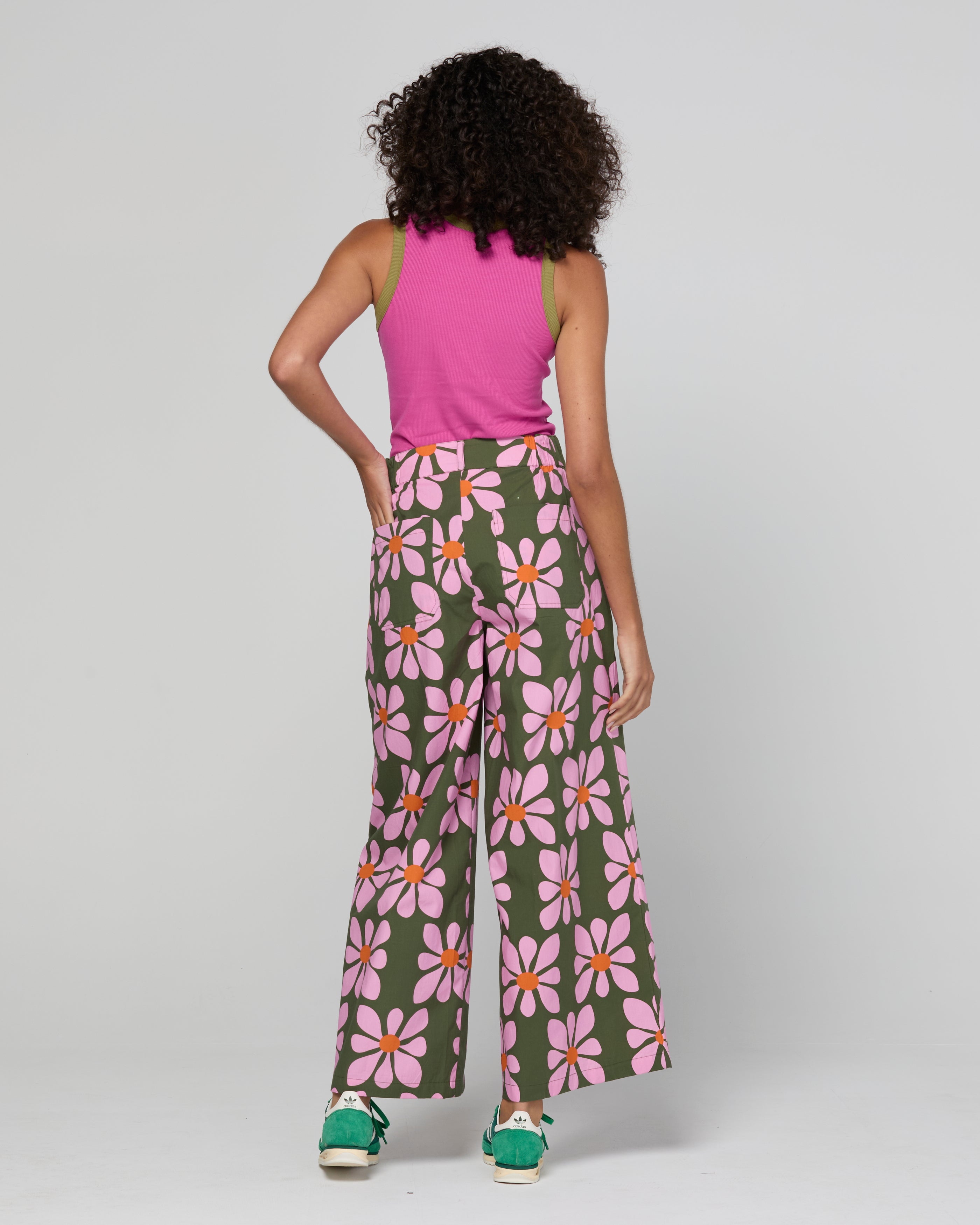 Woman wearing a pink sleeveless top and floral pants on a white background