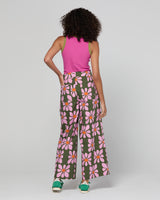 Woman wearing a pink sleeveless top and floral pants on a white background