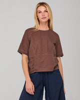 Woman wearing a brown top with stitching design on a gray background