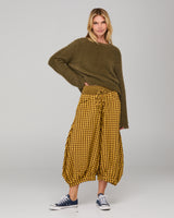 Woman wearing a khaki jumper and mustard plaid gingham pants