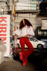 Woman in a white blouse and red pants sitting on a truck with a Japan Kirin sign in the background. 