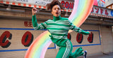 Lady in green striped outfit with rainbow accessories in front of a store with Japanese signage